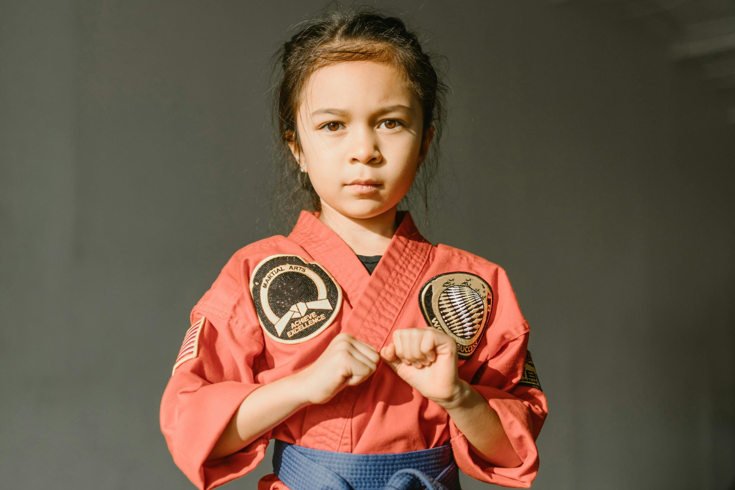 Confident child in a red dobok preparing for martial arts practice. Portrait in warm light.